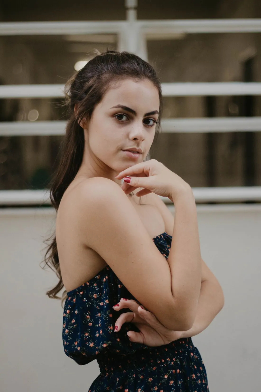 Mujer con un vestido sin hombros de flores pequeñas sobre fondo oscuro.