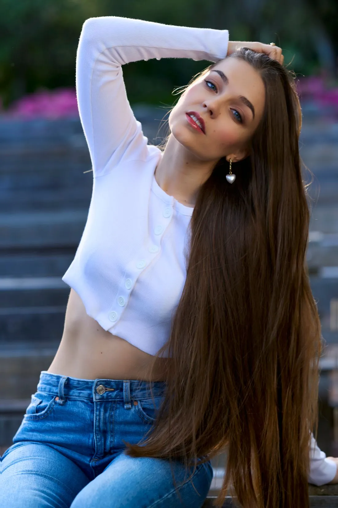 Mujer de cabello largo con una blusa blanca corta de manga larga y jeans.