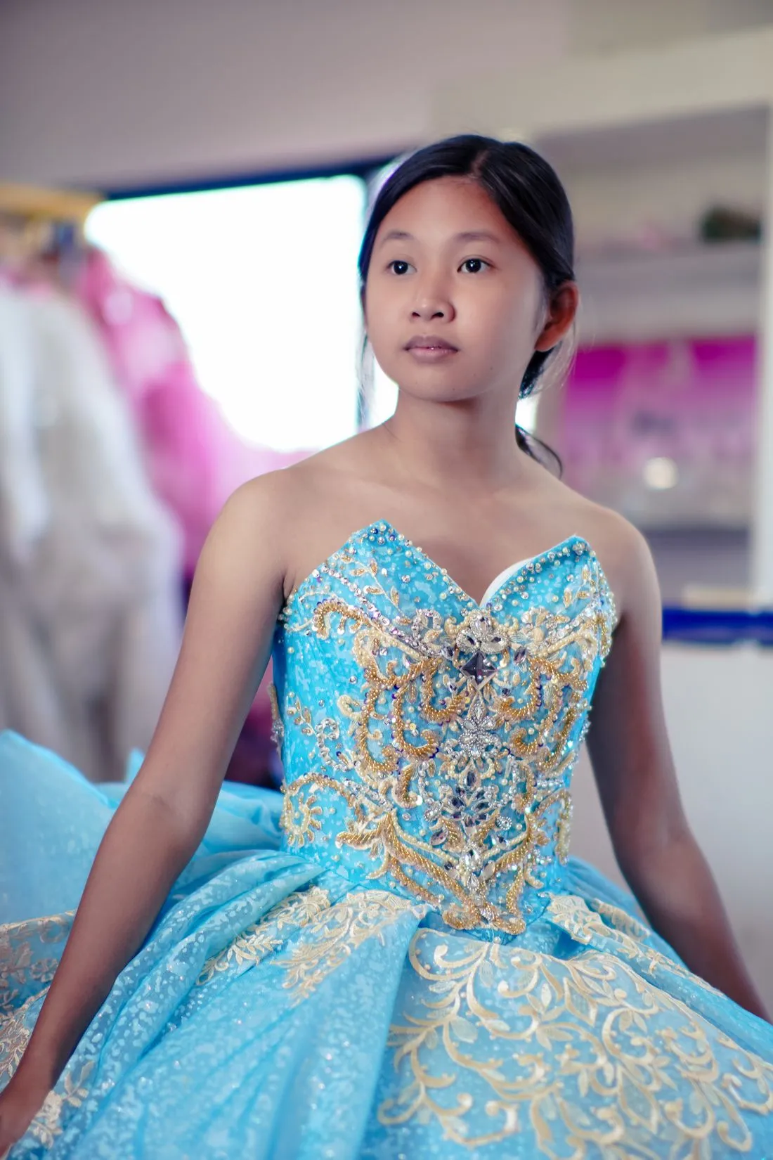 Joven con un vestido turquesa de corpiño bordado en dorado.